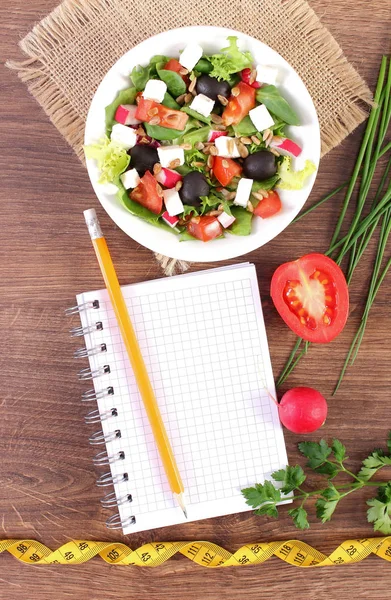 Salade grecque fraîche avec légumes, centimètre et bloc-notes pour écrire des notes, une alimentation saine et un concept minceur — Photo