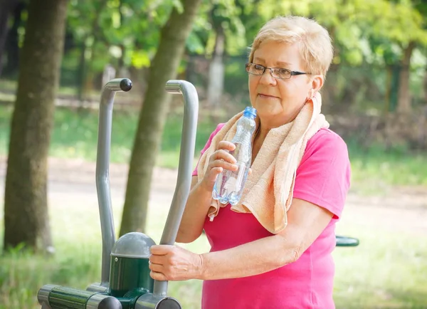 Senior vrouw drinkwater na oefening op outdoor sportschool, gezonde levensstijl — Stockfoto