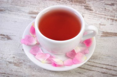 Eski rustik ahşap arka plan üzerinde yabani gül desenli çay