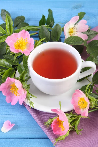 Xícara de chá e flor de rosa selvagem em placas azuis — Fotografia de Stock