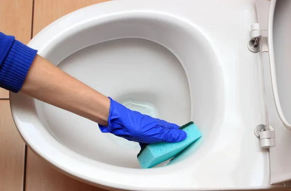 Mão de mulher em luva azul limpeza vaso sanitário — Fotografia de Stock
