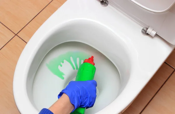 Hand van vrouw in blauwe handschoen reiniging van de toiletpot — Stockfoto