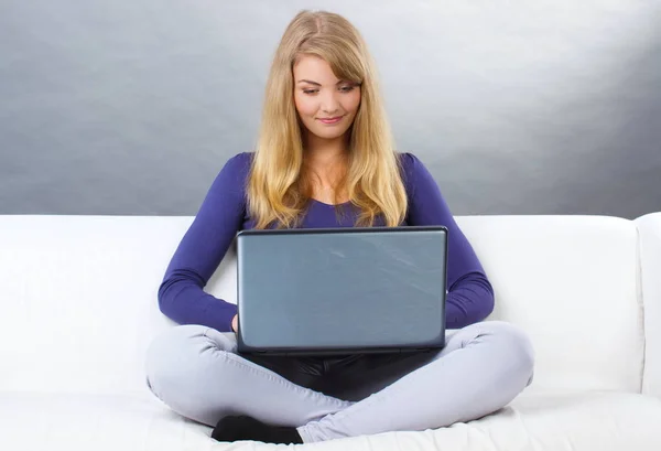 Happy woman using laptop sitting on sofa, modern technology — Stock Photo, Image