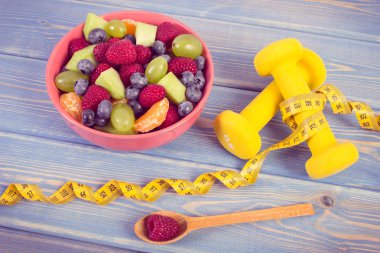 Vintage Fotoğraf, taze meyve salatası ve santimetre dambıl, sağlıklı yaşam ve beslenme kavramı ile