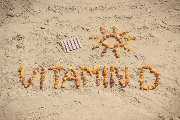 Medical pills, inscription vitamin D and shape of sun on sand at beach, summer time and healthy lifestyle