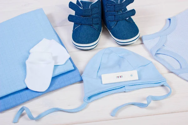 Pregnancy test with positive result and clothing for newborn, expecting for baby