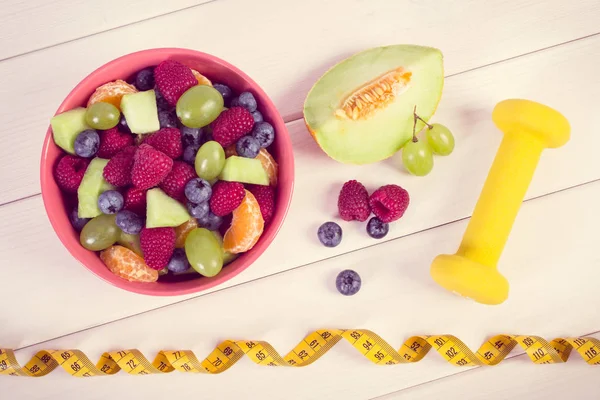 Vintage Fotoğraf, taze meyve salatası ve santimetre dambıl, sağlıklı yaşam ve beslenme kavramı ile