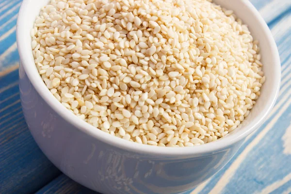 Heap of sesame seeds in white bowl on wooden boards — Stock Photo, Image