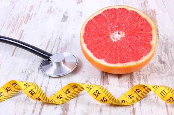 Fresh grapefruit, centimeter and stethoscope on old wooden background — Stock Photo, Image