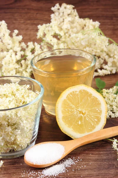 Flores y zumo de saúco, ingredientes para preparar bebidas sobre tabla rústica — Foto de Stock