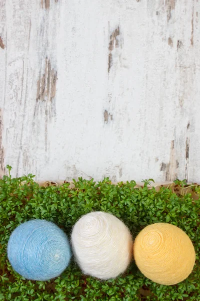 Velikonoční vejce zabalená vlněné řetězec a zelená Řeřicha na dřevěné pozadí, kopírování prostor pro text, dekorace na Velikonoce — Stock fotografie
