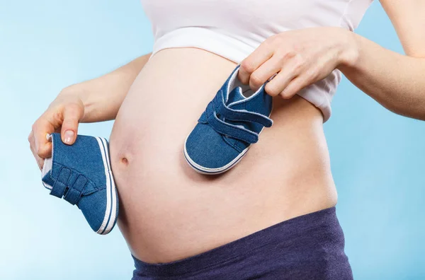 Mujer embarazada con zapatos de bebé, esperando un bebé — Foto de Stock