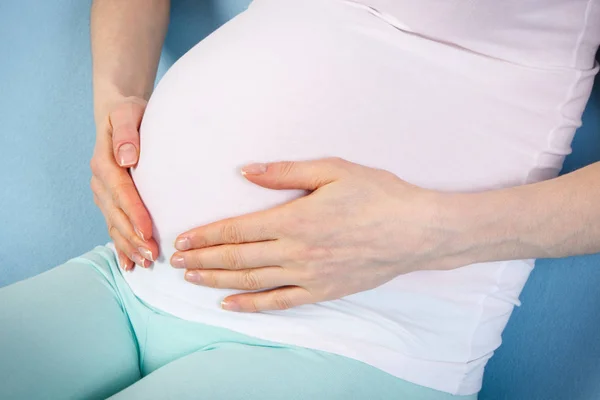 Беременная женщина держит руки на животе, ожидая ребенка — стоковое фото