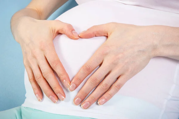Беременная женщина держит руки на животе, ожидая ребенка — стоковое фото