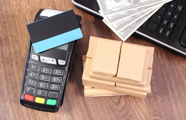 Terminal de pago con tarjeta de crédito, monedas dólar, laptop y cajas envueltas en paleta de madera — Foto de Stock