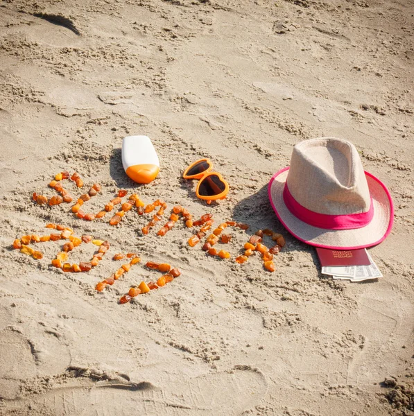 Inscripción verano 2017, accesorios para tomar el sol y pasaporte con monedas dólar en la arena en la playa, hora de verano — Foto de Stock