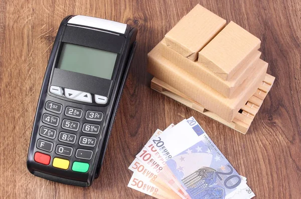Payment terminal, currencies euro and wrapped boxes on wooden pallet, concept of paying for products — Stock Photo, Image