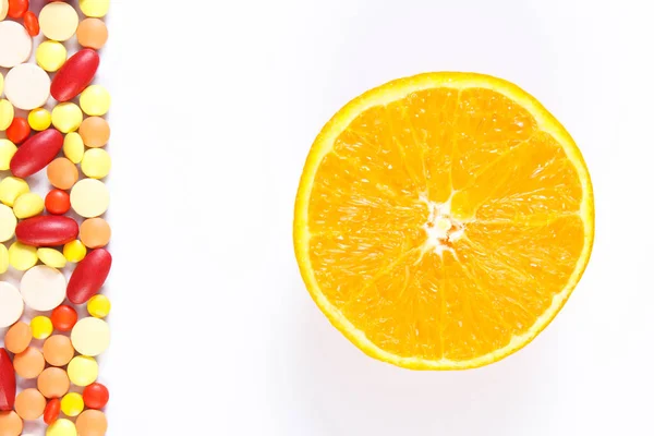 Coloridas píldoras médicas y naranja fresca sobre fondo blanco, cuidado de la salud y el concepto de estilo de vida saludable —  Fotos de Stock