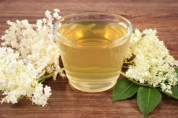 Fresco jugo sano y flores de saúco en tablero rústico — Foto de Stock