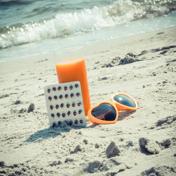 Foto d'epoca, pillole mediche, succo di carota e occhiali da sole sulla sabbia in spiaggia, vitamina A e bella, abbronzatura duratura — Foto Stock