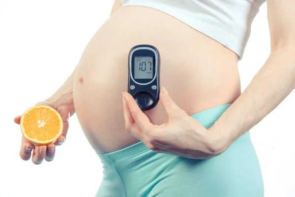 Mujer embarazada con glucosímetro y naranja, diabetes y nutrición saludable durante el embarazo — Foto de Stock