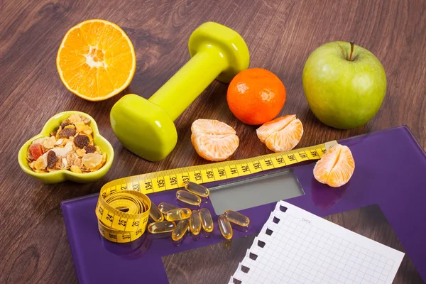 Escala digital con cinta métrica, tabletas, pesas, frutas, muesli, concepto de adelgazamiento — Foto de Stock