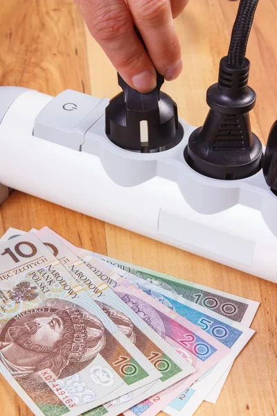 Mão da mulher desliga ficha elétrica, dinheiro de moeda polonês, custos de energia — Fotografia de Stock