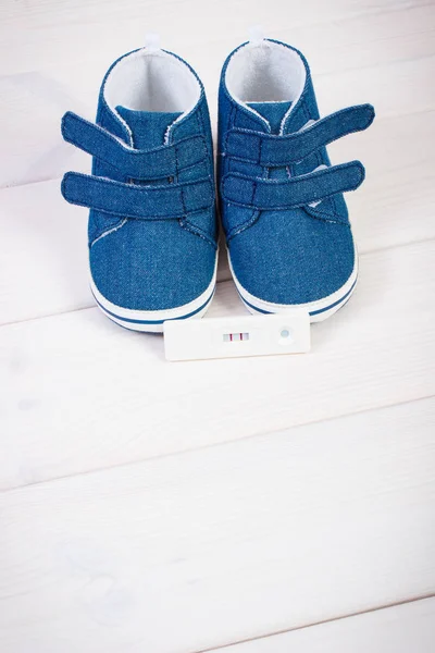 Teste de gravidez com resultado positivo e sapatos de bebê para recém-nascido, esperando para o bebê — Fotografia de Stock