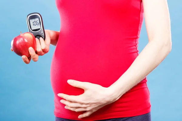Zwangere vrouw met appel en glucose meter met goed resultaat suikerniveau, diabetes en voeding tijdens de zwangerschap — Stockfoto
