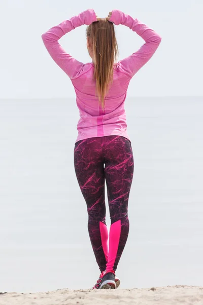 Chica delgada en ropa deportiva haciendo ejercicio en la playa en el mar, estilo de vida activo saludable — Foto de Stock