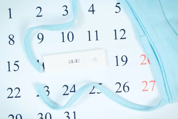 Foto vintage, test di gravidanza con risultato positivo e cappuccio per neonato sul calendario, in attesa per il bambino — Foto Stock