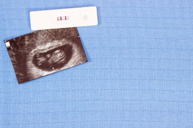 Hamilelik testi ve ultrason bebek için bekliyor bebek bezi, arka plan üzerinde inceden inceye gözden geçirmek