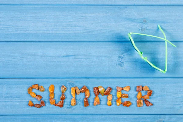 Palabra de verano hecha de piedras ámbar y gafas de sol en tablas azules, hora de verano, espacio de copia para el texto —  Fotos de Stock