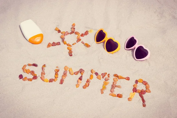Форма солнца и слова лето, солнцезащитные очки и крем для загара на песке на пляже — стоковое фото