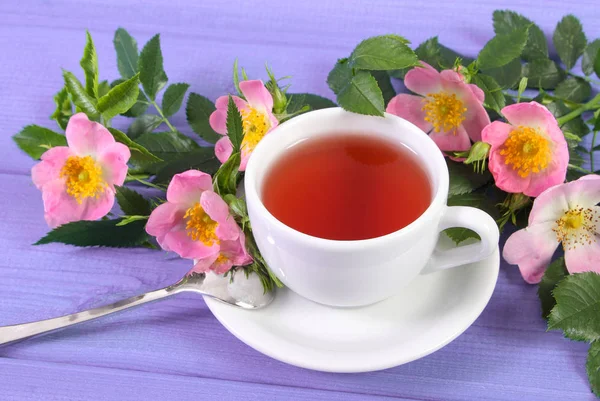 Xícara de chá quente e flor de rosa selvagem em placas — Fotografia de Stock
