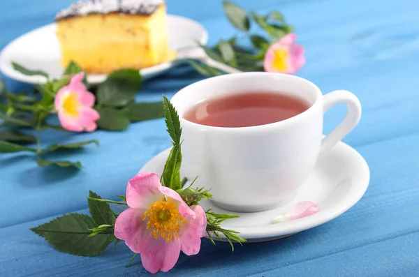 Varm te med ostekake og villroseblomst på bord – stockfoto