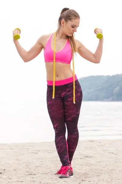 Smal tjej i sportkläder som tränar med hantlar på stranden, begreppet sport livsstil och bantning koncept — Stockfoto