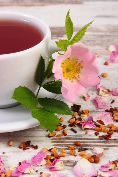 Tasse heißer Tee mit Wildrosenblume auf alten rustikalen Planken — Stockfoto