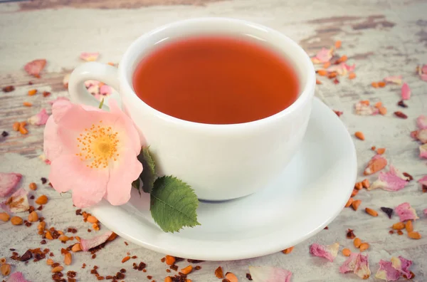 Vintage foto, xícara de chá com flor de rosa selvagem na placa rústica velha — Fotografia de Stock