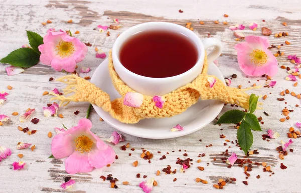 Kopje warme thee met wild rose bloem op rustieke houten achtergrond — Stockfoto
