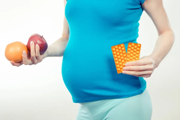 Vintage foto, zwangere vrouw met vruchten en medische pillen of supplementen, keuze tussen gezonde voeding en pillen tijdens de zwangerschap — Stockfoto