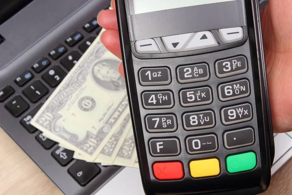 Using payment terminal, currencies dollar on laptop in background — Stock Photo, Image