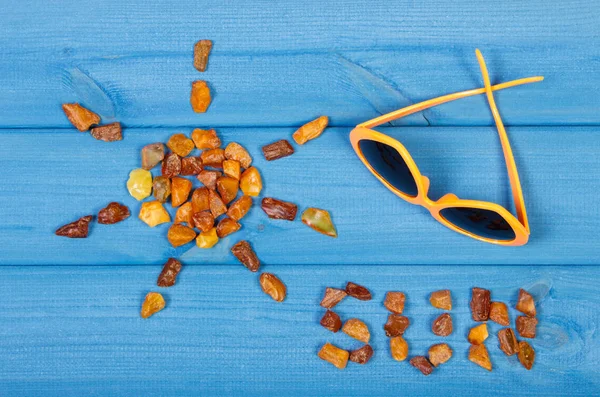 Форма солнца со словом солнце из янтарных камней и солнцезащитных очков — стоковое фото