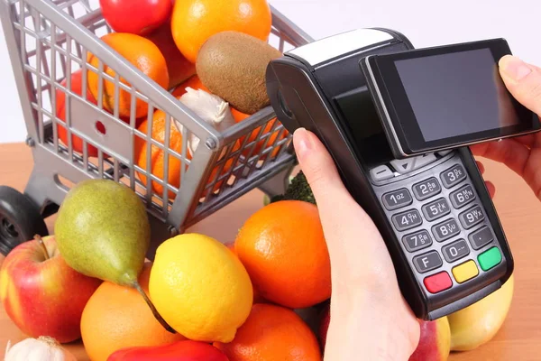 Terminal de pago y teléfono móvil con tecnología NFC, frutas y verduras, concepto de pago sin efectivo para compras — Foto de Stock