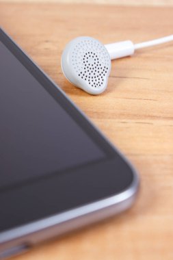 Ahşap masa üzerinde kulaklık ile cep telefonu