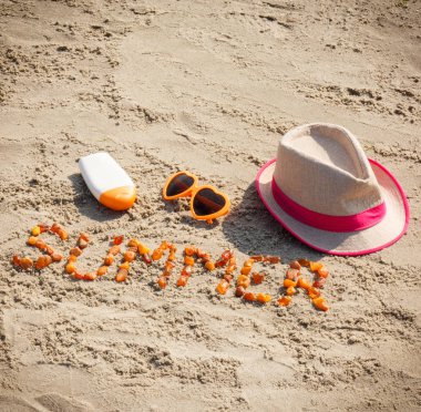 Kelime yaz, güneş gözlüğü, güneş losyon ve straw hat kum üzerinde yaz saati kavramı