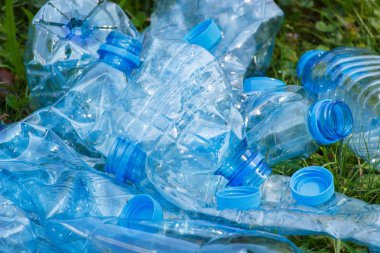 Plastik şişe ve şişe kapakları Park, çevre çöp kavramı yeşil çimenlerin üzerinde