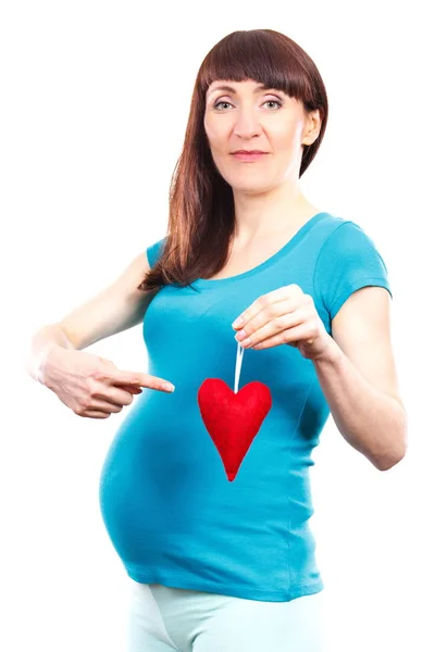 Щаслива жінка у вагітних показує червоне серце, символ нового життя, концепція очікування новонародженого — стокове фото