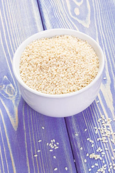 Sesame seeds in white bowl on wooden boards, healthy nutrition — Stock Photo, Image