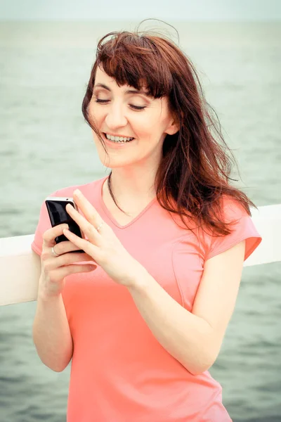 Foto vintage, mulher sorridente mensagem de texto em seu smartphone — Fotografia de Stock